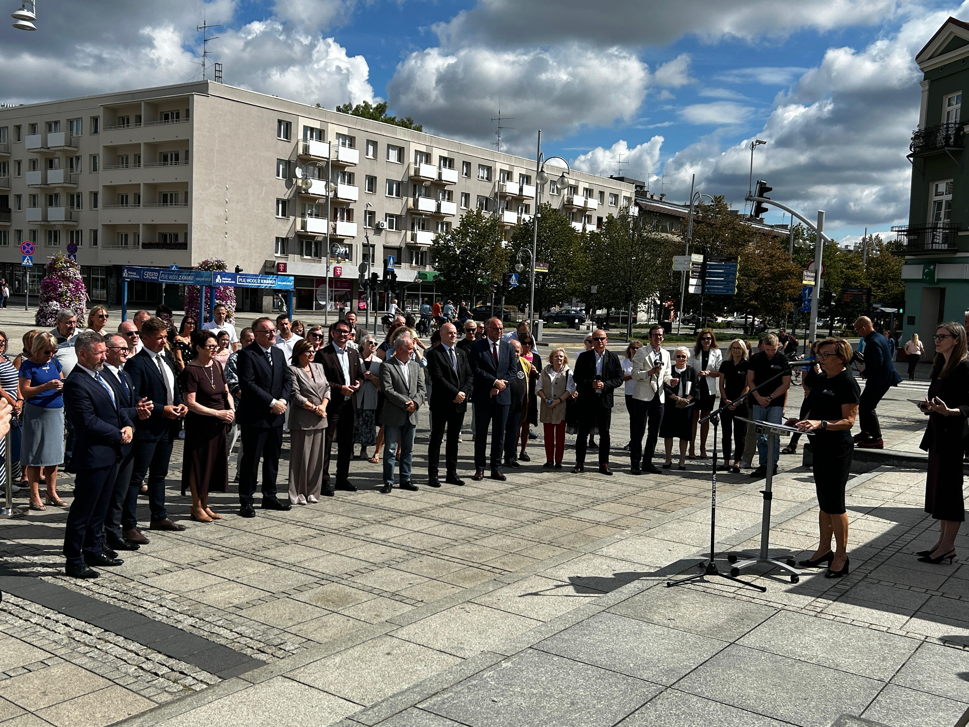 grupa ludzi słucha przemawiającej kobiety