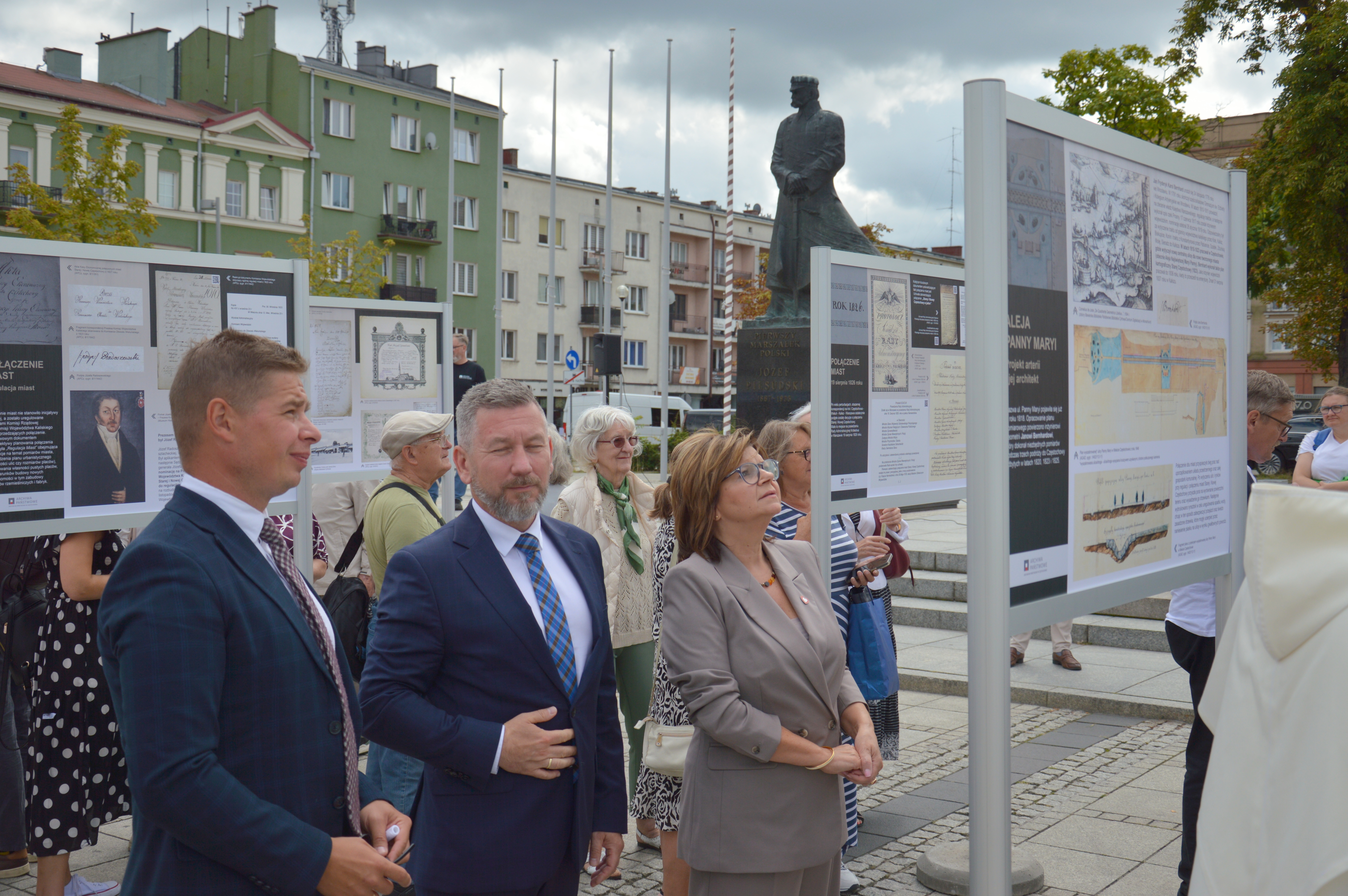 dwóch mężczyzn i kobieta ogląda wystawę na planszy